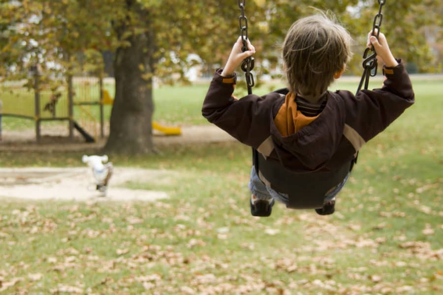 A child on a swing at a playground in autumn for a blog on national childhood injury prevention week