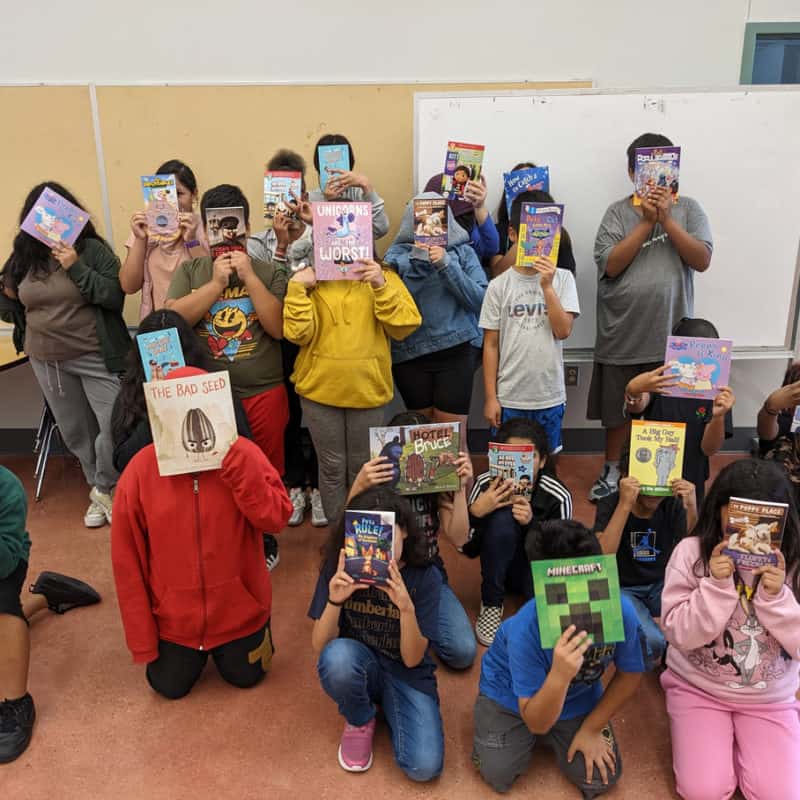 A classroom of students at Hillcrest Elementary holding up books from their book fair after partnering with Ally Medical