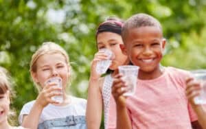 Kids staying cool and hydrated in the heat by drinking plenty of water! Remember, staying hydrated is key to having fun in the sun.