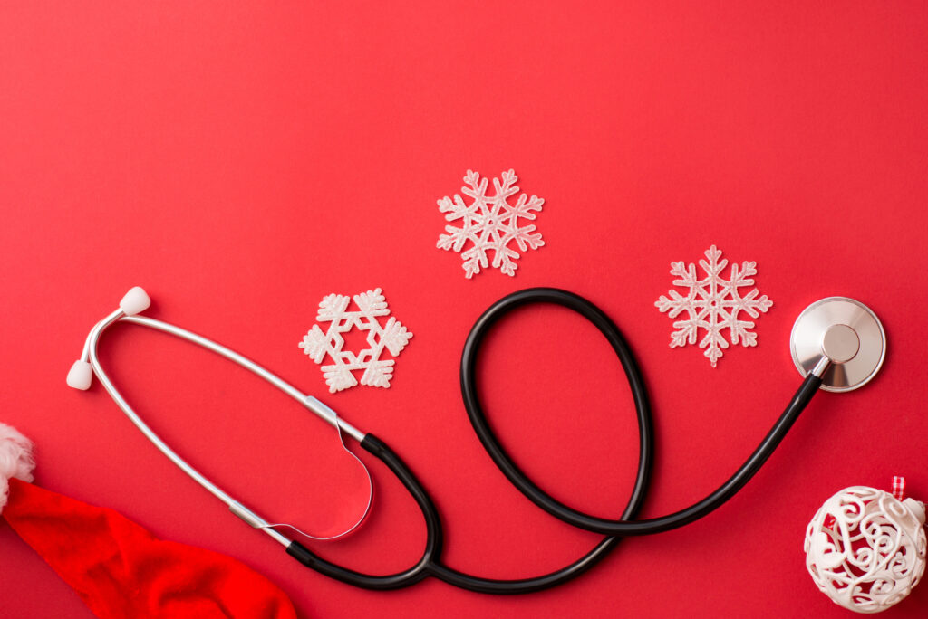 stethoscope and Christmas decoration on red background, winter medicine card